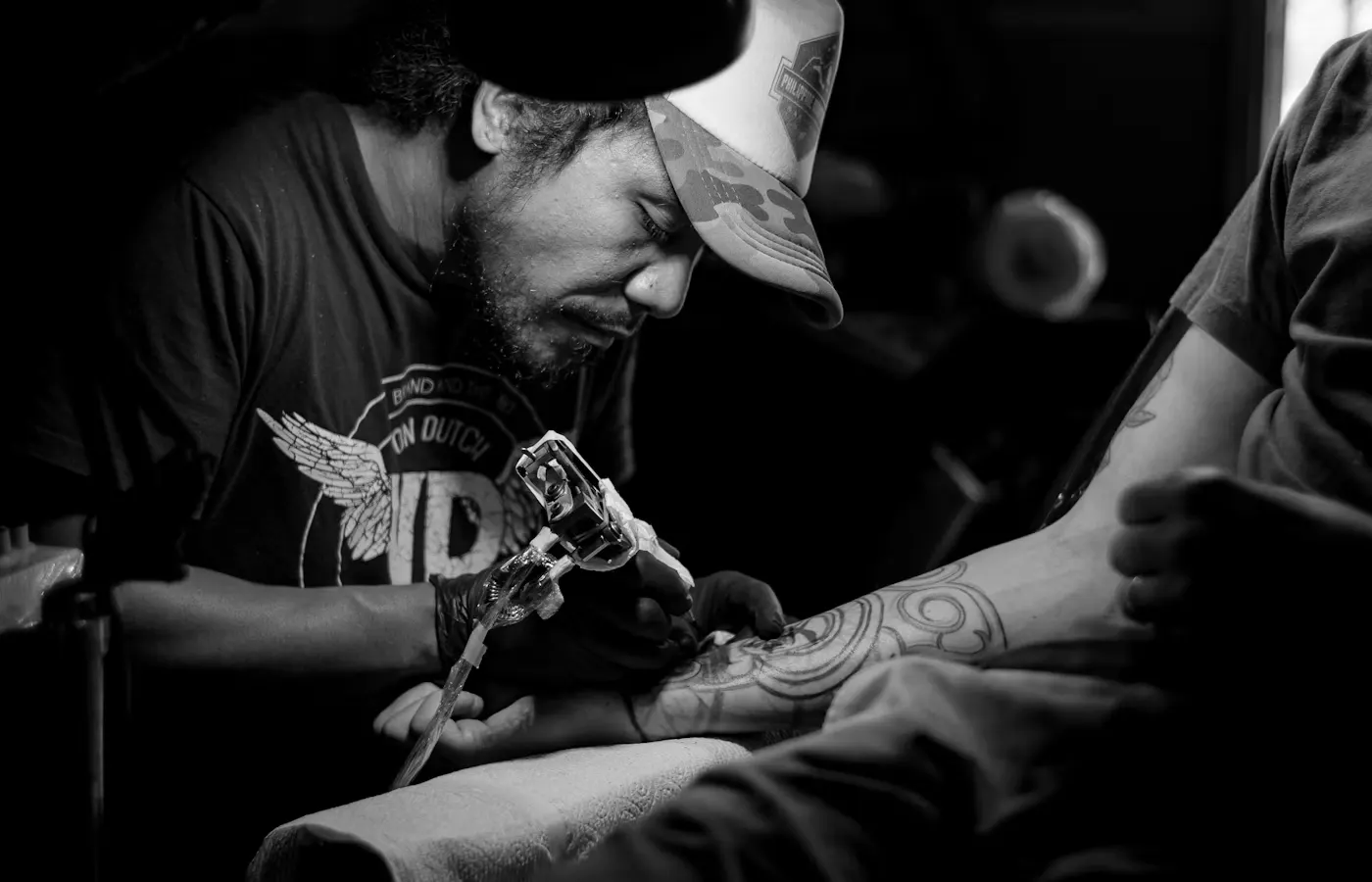Tatuador fazendo uma tatuagem no antebraço de um cliente
